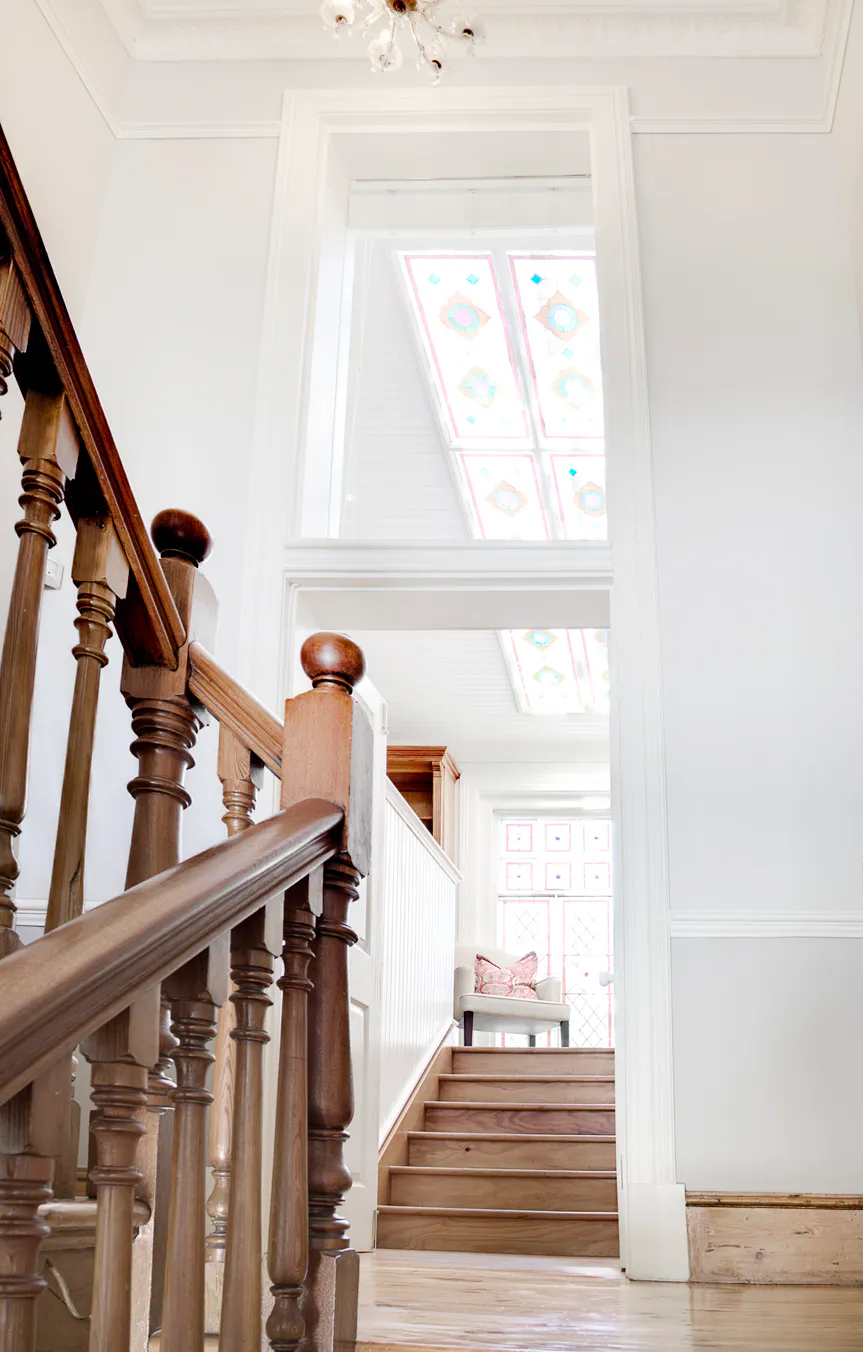 Main staircase and stained-glass landing leading to Room Six