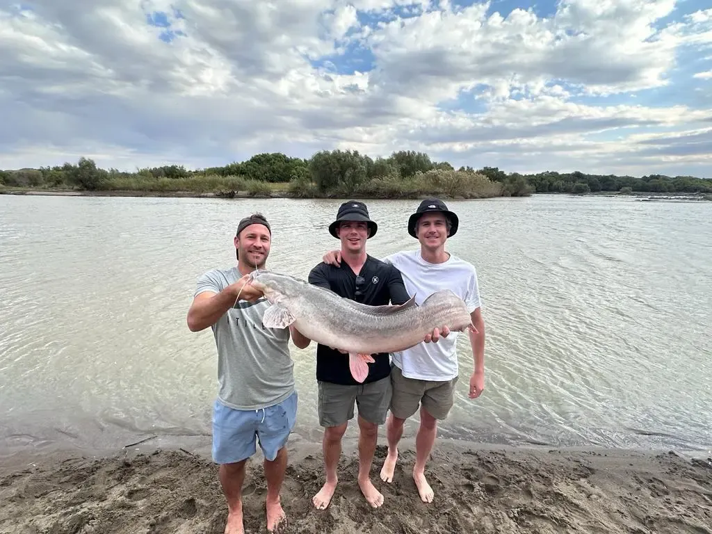 Guests holding a large fish beside the Orange River