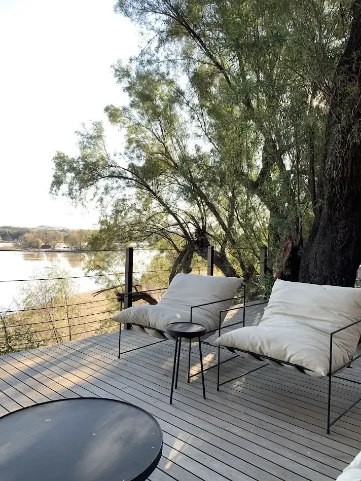 Riverside lounge seating beneath the trees