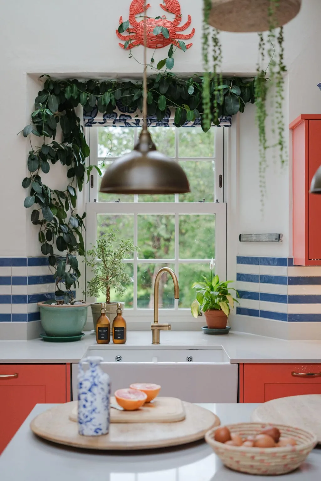 The kitchen sink at Lawton House with coral cabinetry and a brass tap