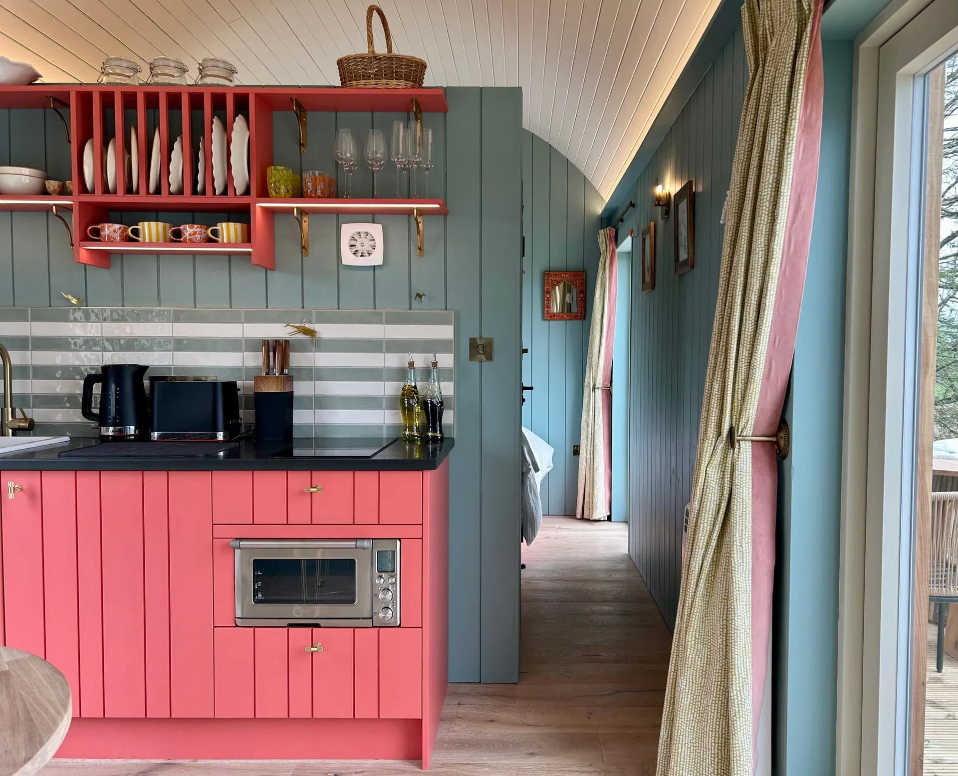 Milkwood's kitchen with pink cabinetry and a pale blue hallway