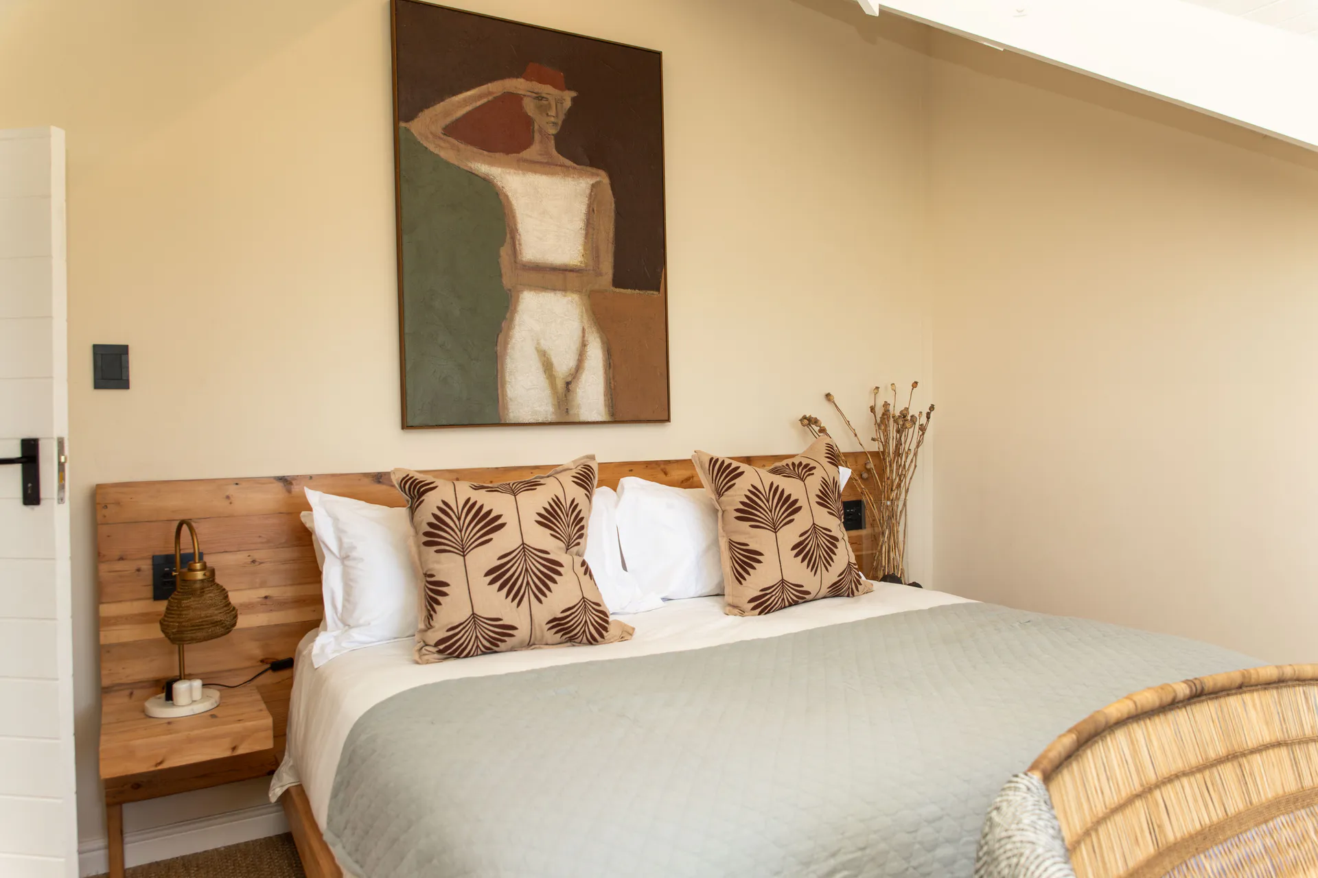 Sea Facing Apartment bed with patterned pillows and figure painting