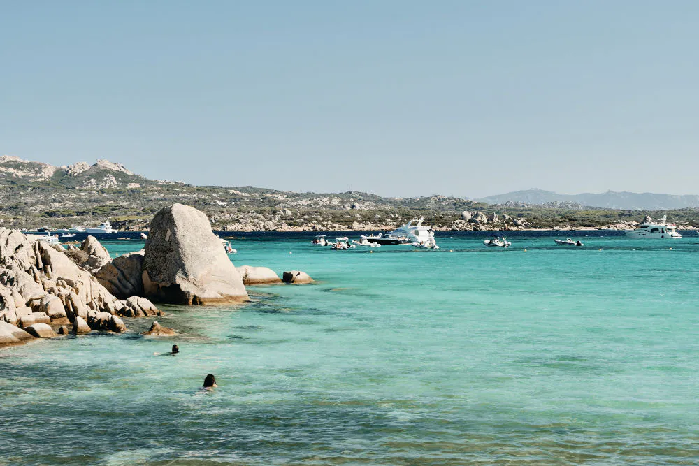 Turquoise West Coast bay with rocky shoreline and boats at anchor, used as a Yzerfontein atmosphere image