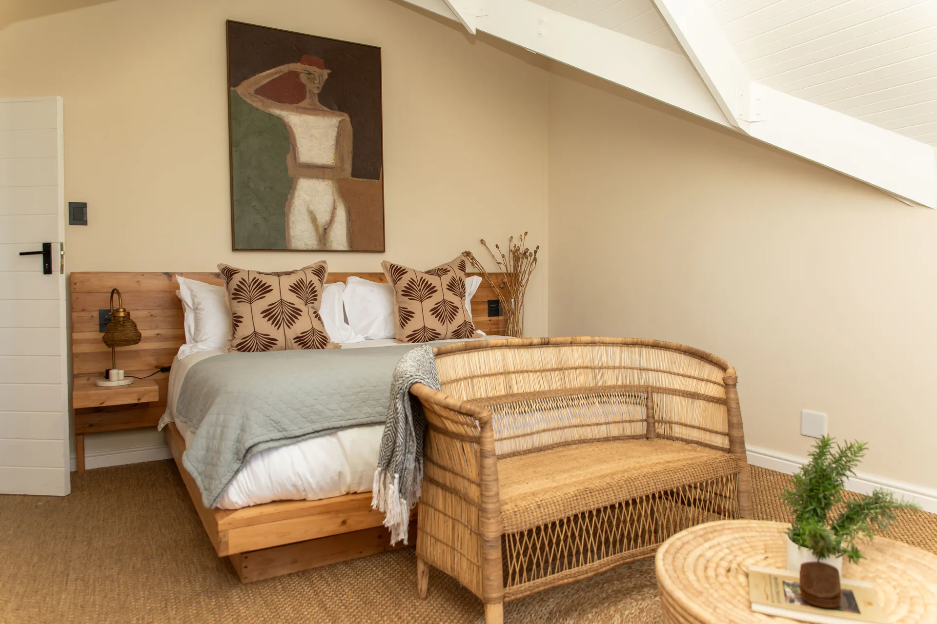 Sea Facing Apartment bedroom with rattan bench and figure painting
