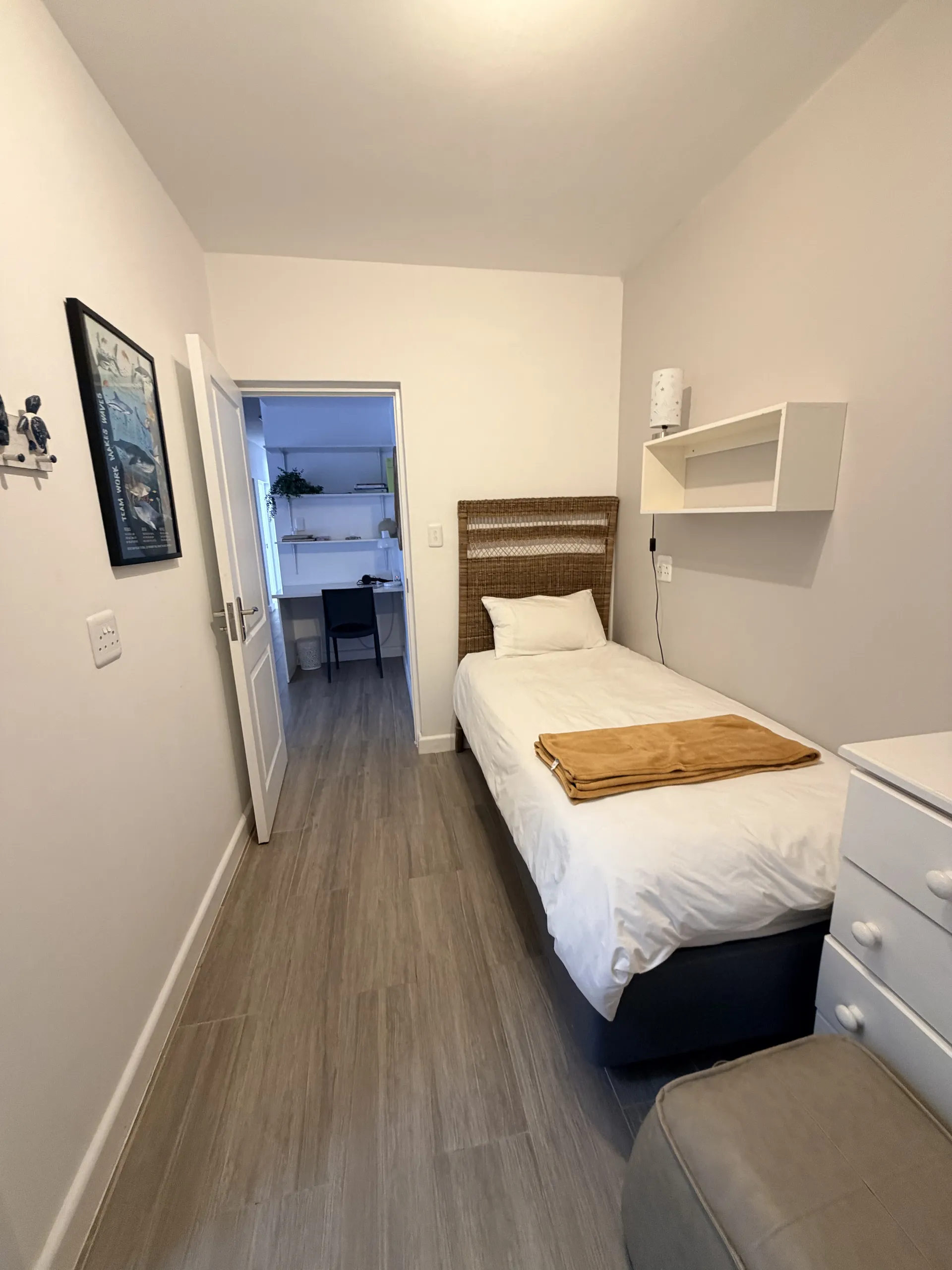 Twin bedroom with a woven headboard and mustard throw