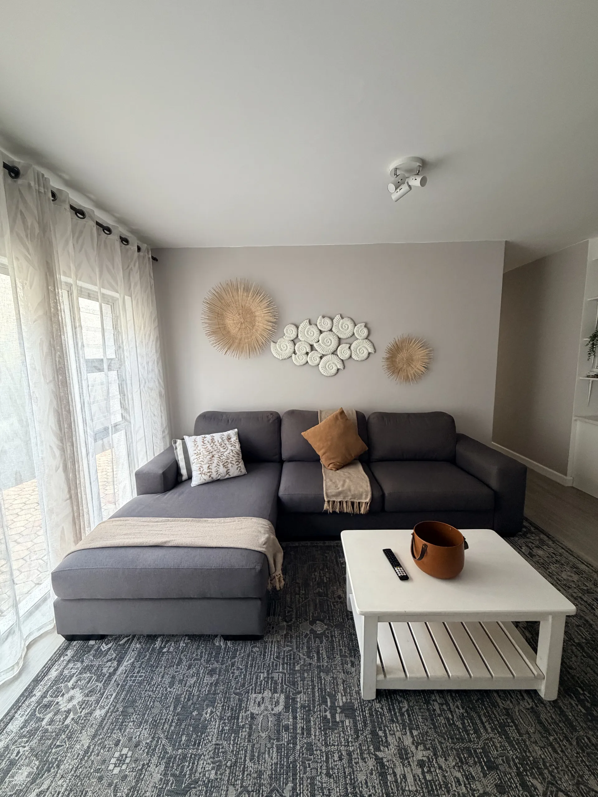 Living room with a grey sectional, coffee table and woven wall art