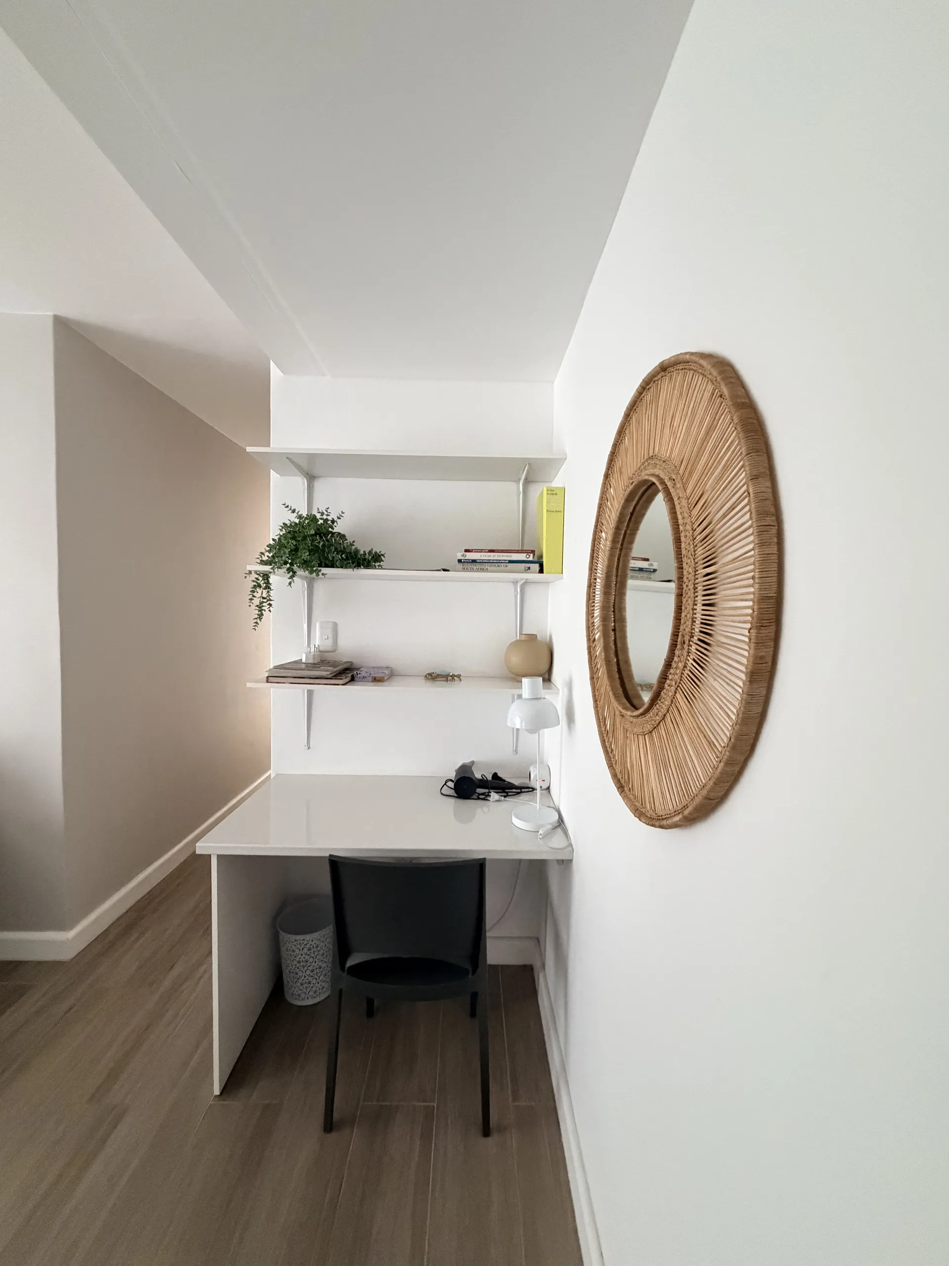 Desk nook with a rattan mirror and floating shelves