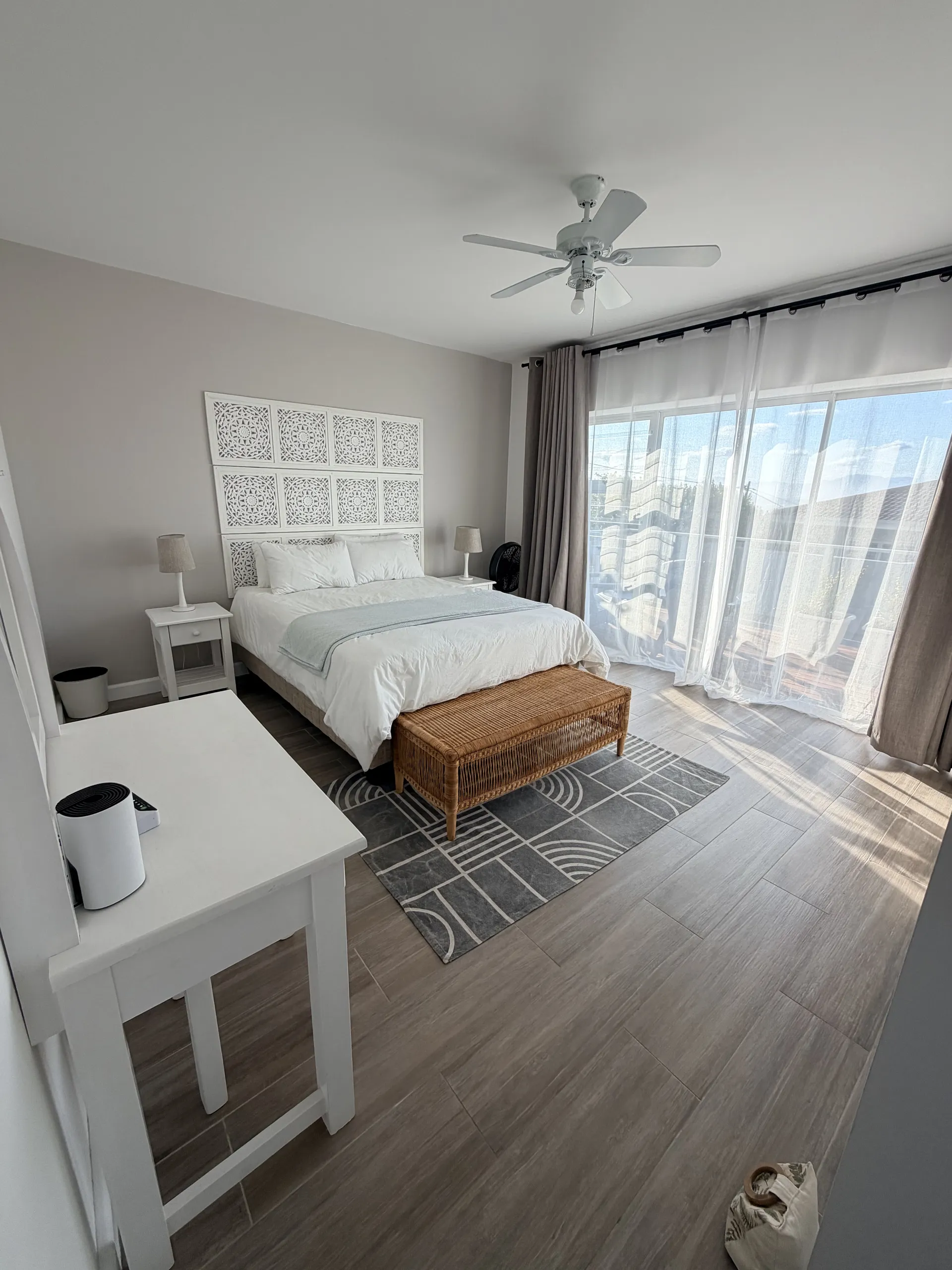 Bedroom with a carved headboard, rattan bench and balcony light