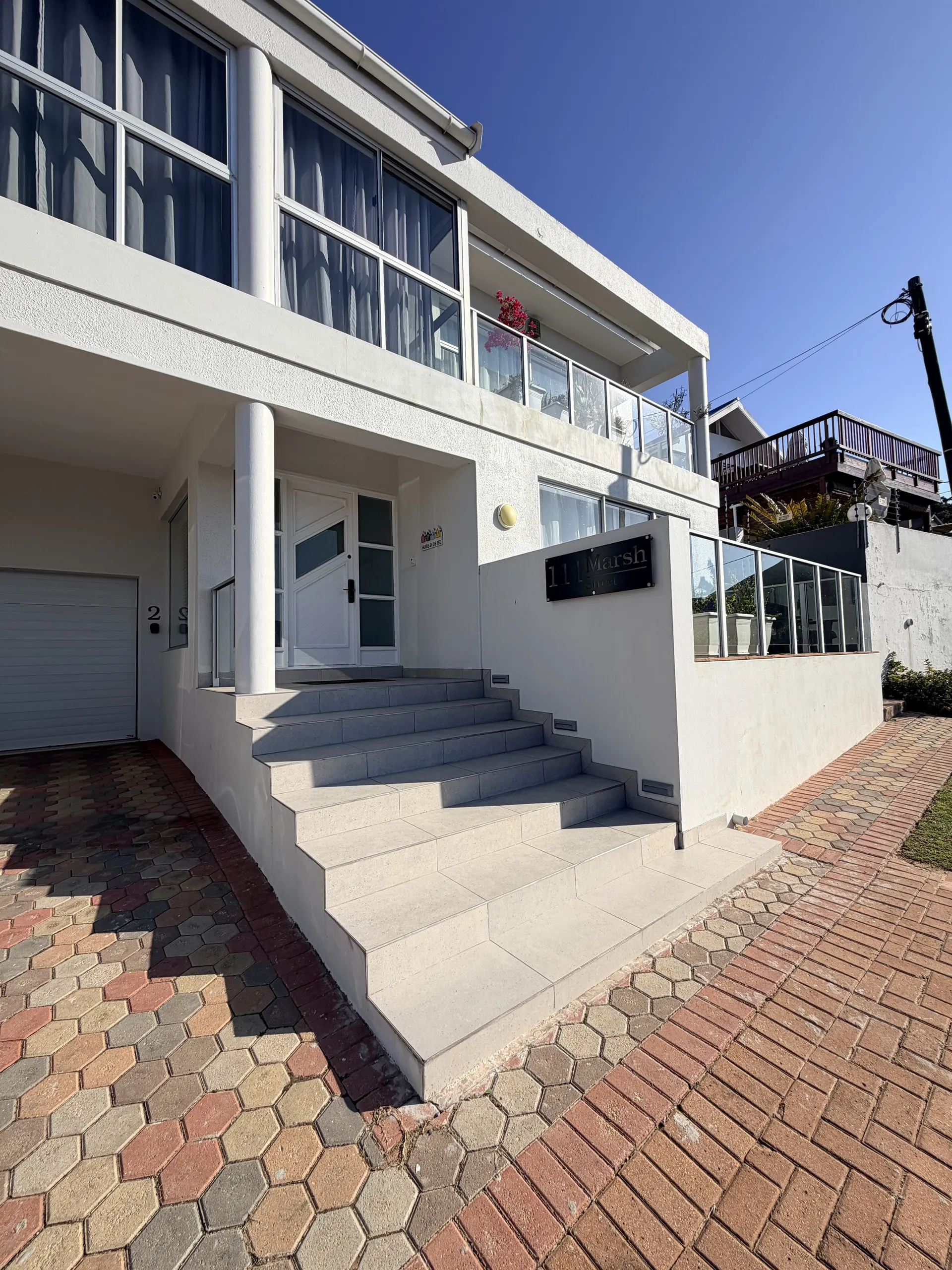 Coastal Charm entrance at 11 Marsh with tiled steps and a first-floor balcony